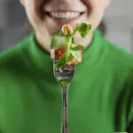 Donna che mangia Piatto sano ed equilibrato con carboidrati, proteine, verdure e grassi buoni disposto in modo semplice e naturale