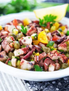 Insalata di polpo tenero con patate lesse, prezzemolo fresco e olive, servita in una bowl moderna, stile RicetteFit