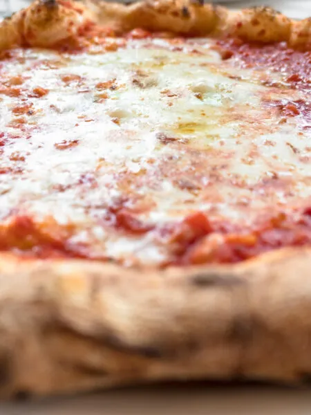 Pizza margherita integrale fatta in casa con pomodoro, mozzarella light e basilico fresco su pietra refrattaria, stile RicetteFit.