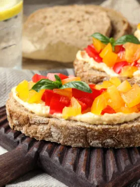 Crostini di pane integrale con hummus di ceci e fiocchi di latte freschi, decorati con granella di pistacchi e paprika, stile RicetteFit.
