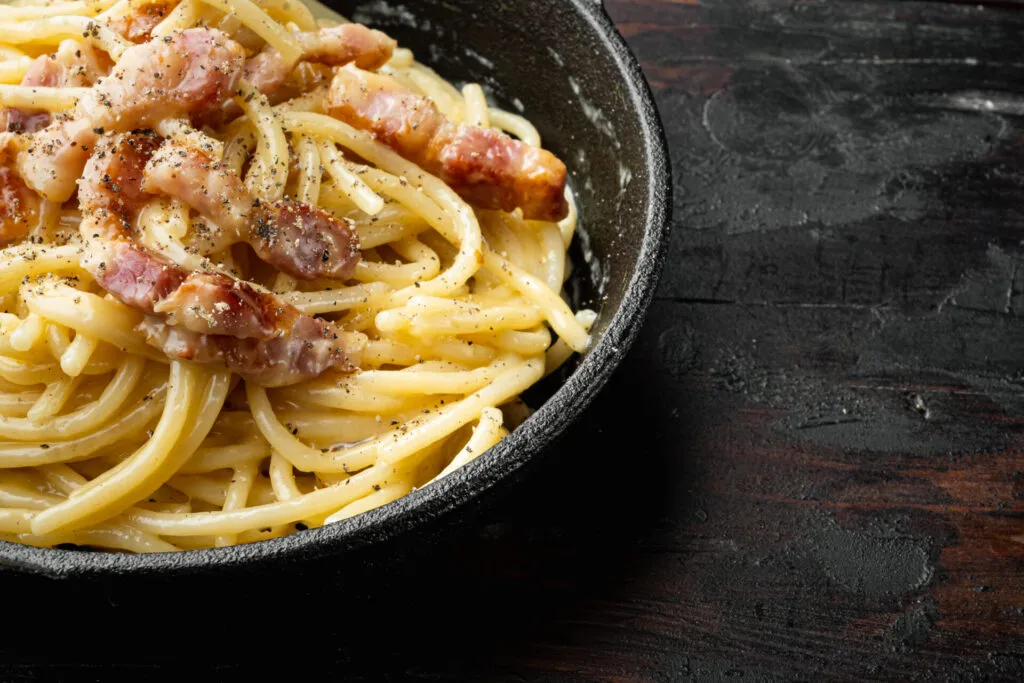 Pasta alla carbonara fit con crema di uova e pecorino leggero, guarnita con cubetti di bresaola croccante o guanciale magro, stile RicetteFit.