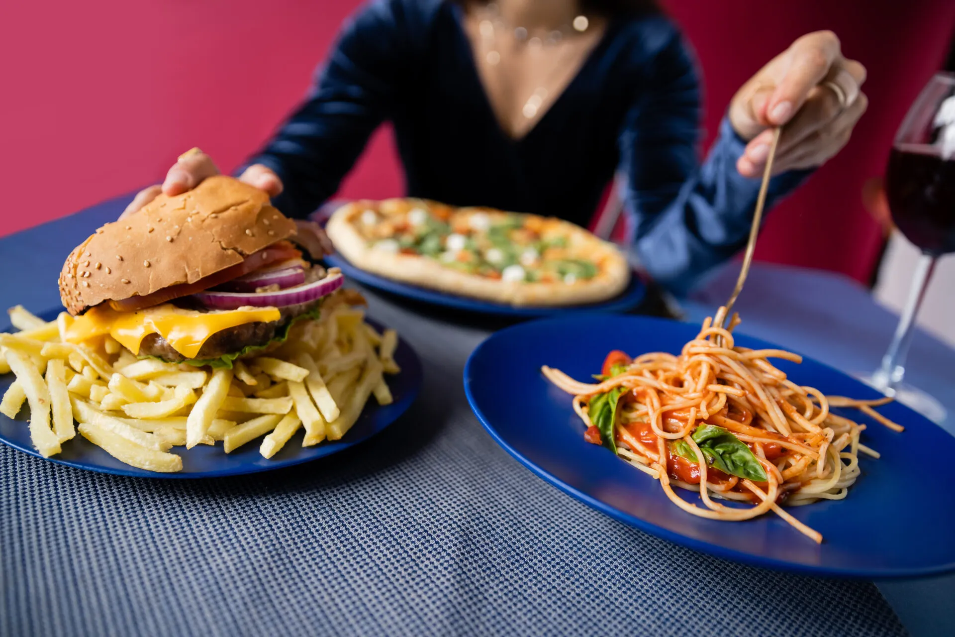 Hamburger con patatine fritte accanto a un piatto di spaghetti al pomodoro, esempio di confronto tra cibo spazzatura e alimentazione sana.
