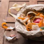 Scarti alimentari di verdure e gusci d’uovo raccolti in un sacchetto di carta, pronti per essere riutilizzati in cucina o trasformati in compost per ridurre gli sprechi alimentari.