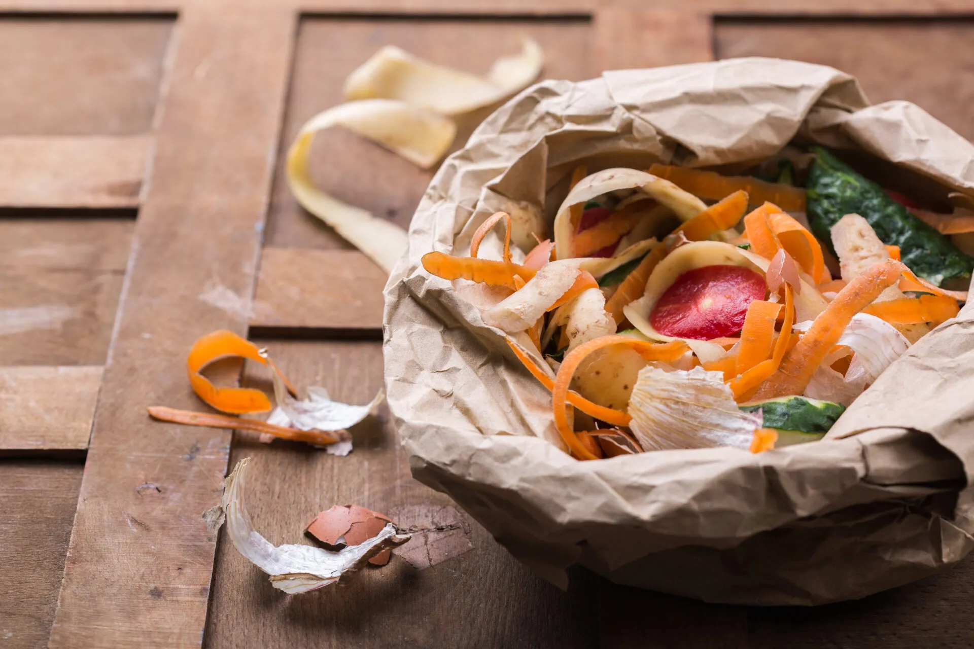 Scarti alimentari di verdure e gusci d’uovo raccolti in un sacchetto di carta, pronti per essere riutilizzati in cucina o trasformati in compost per ridurre gli sprechi alimentari.