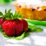 Primo piano di fragole fresche con torta sullo sfondo sfocato, immagine perfetta per dolci semplici e golosi con le fragole