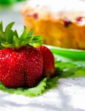 Primo piano di fragole fresche con torta sullo sfondo sfocato, immagine perfetta per dolci semplici e golosi con le fragole