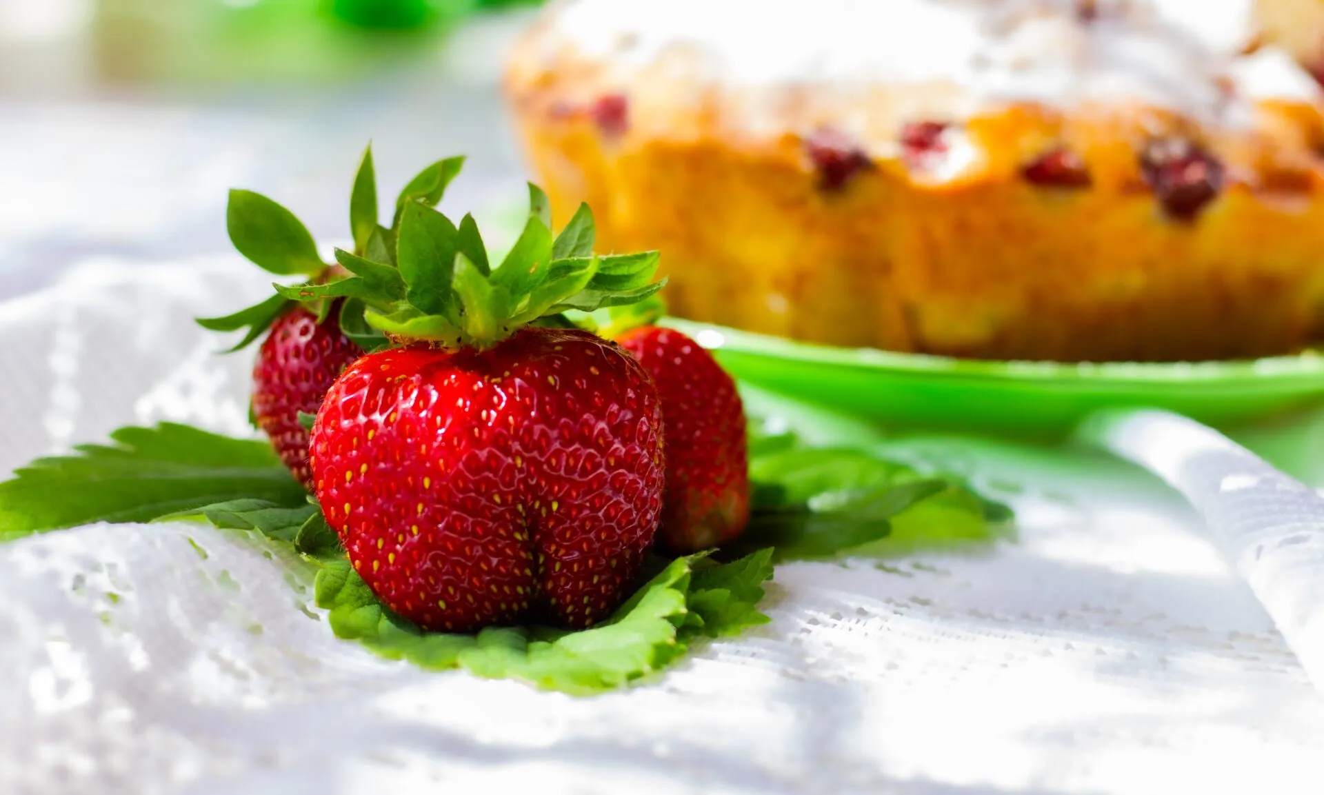 Primo piano di fragole fresche con torta sullo sfondo sfocato, immagine perfetta per dolci semplici e golosi con le fragole