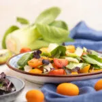 Insalata light estiva con finocchi, pomodorini colorati, agrumi e foglie verdi servita in un piatto su tavola chiara.