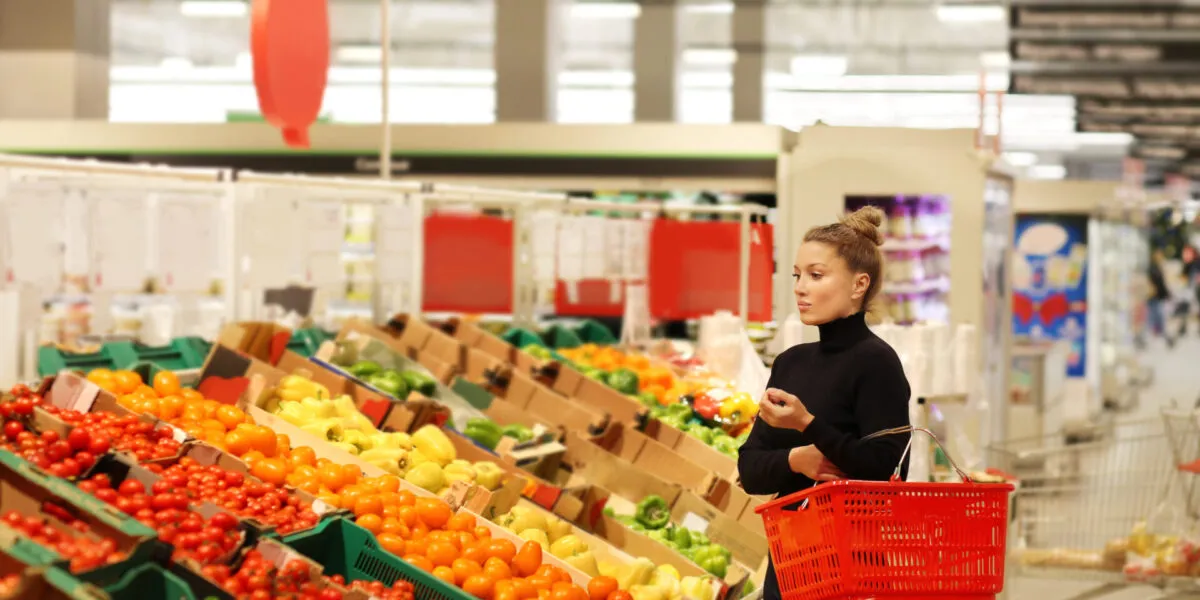 Donna che fa la spesa nel reparto ortofrutta di Lidl tra pomodori, peperoni e verdure fresche in offerta nel volantino di maggio.