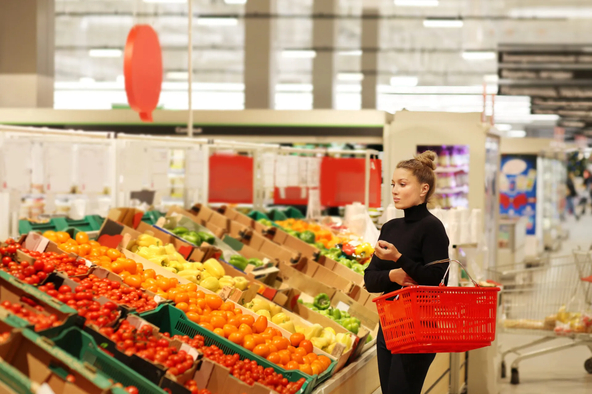 Donna che fa la spesa nel reparto ortofrutta di Lidl tra pomodori, peperoni e verdure fresche in offerta nel volantino di maggio.