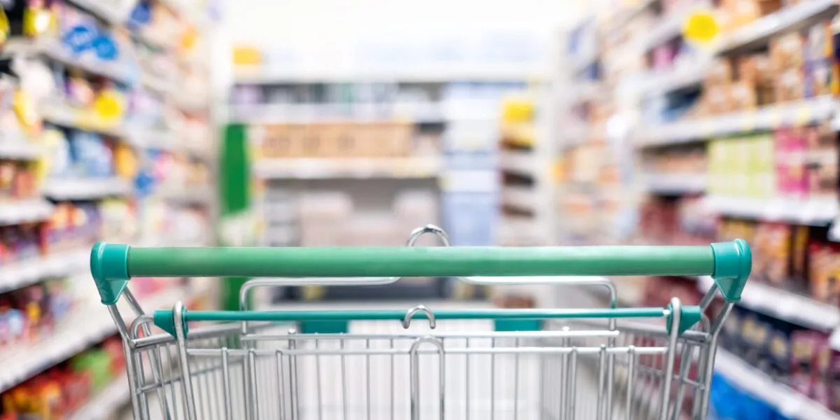 Carrello della spesa in un supermercato con corsie piene di prodotti, immagine dedicata al confronto dei supermercati più economici.