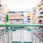 Carrello della spesa in un supermercato con corsie piene di prodotti, immagine dedicata al confronto dei supermercati più economici.
