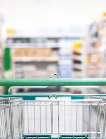 Carrello della spesa in un supermercato con corsie piene di prodotti, immagine dedicata al confronto dei supermercati più economici.