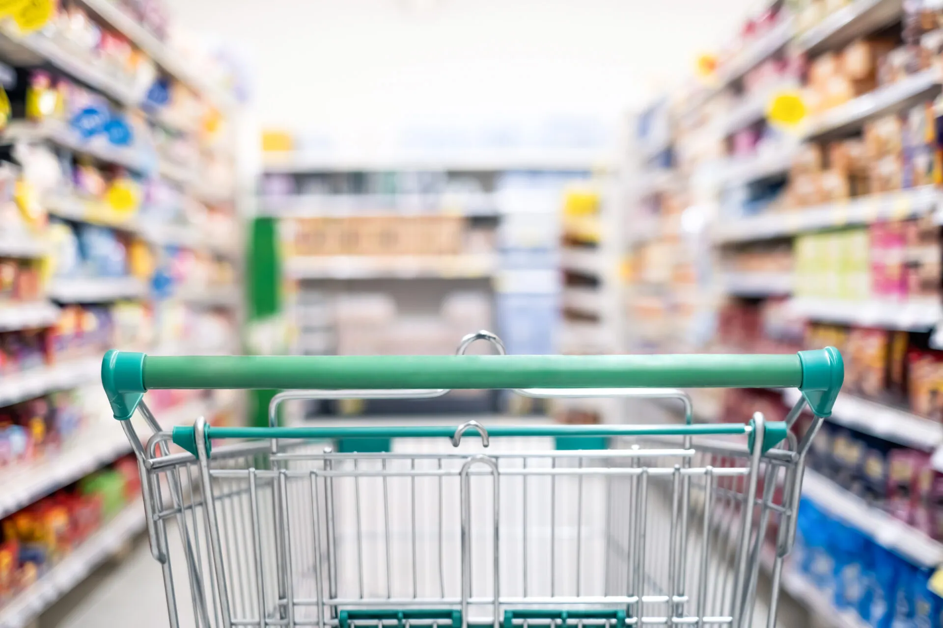 Carrello della spesa in un supermercato con corsie piene di prodotti, immagine dedicata al confronto dei supermercati più economici.