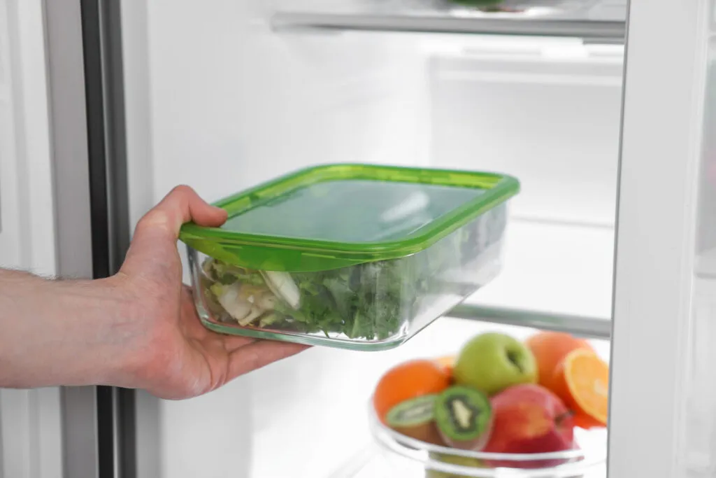 Contenitore con scarti di verdure conservati in frigorifero per essere riutilizzati in nuove ricette, riducendo lo spreco alimentare domestico.