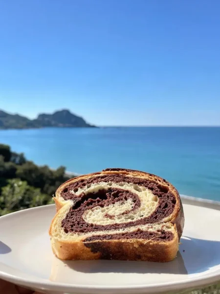 Fetta di babka brioche vegana al cacao su piatto bianco vista mare a Cefalù
