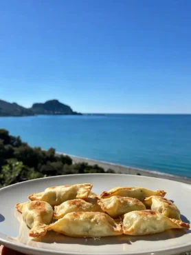 Fagottini fit di pasta brisè e mela su piatto con vista mare a Cefalù