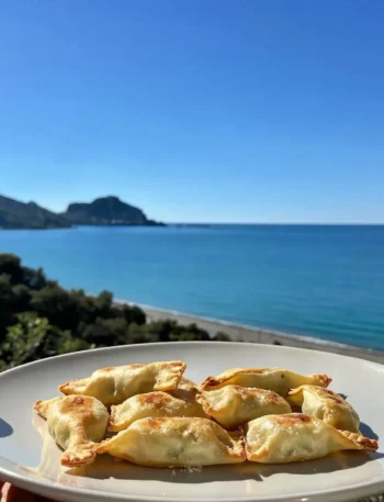 Fagottini fit di pasta brisè e mela su piatto con vista mare a Cefalù