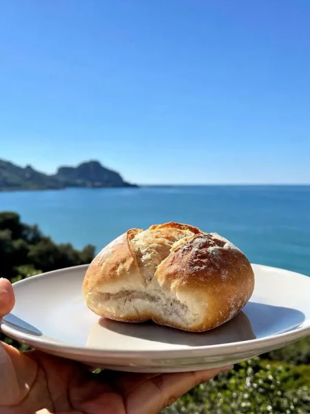 Panino senza olio su piatto bianco con vista mare a Cefalù