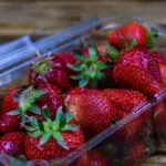 Fragole fresche in una vaschetta trasparente: guida pratica su come conservare le fragole in frigorifero e prevenire la formazione di muffa.