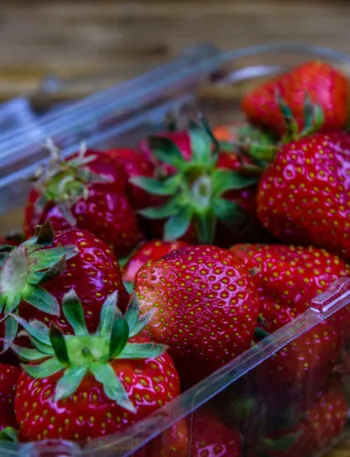 Fragole fresche in una vaschetta trasparente: guida pratica su come conservare le fragole in frigorifero e prevenire la formazione di muffa.