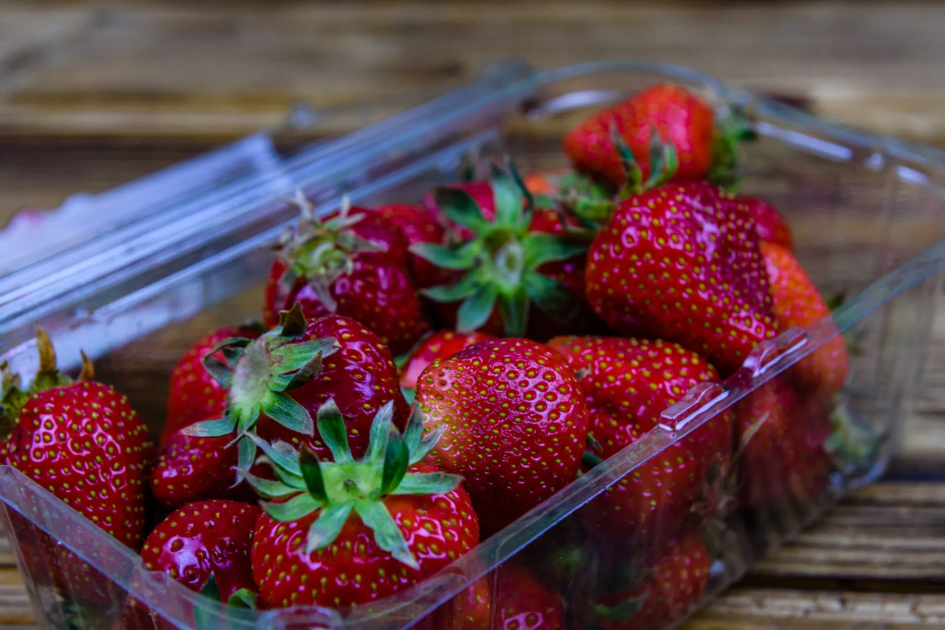 Fragole fresche in una vaschetta trasparente: guida pratica su come conservare le fragole in frigorifero e prevenire la formazione di muffa.