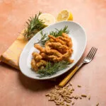 Panatura croccante al forno con bocconcini impanati dorati serviti con limone e rosmarino