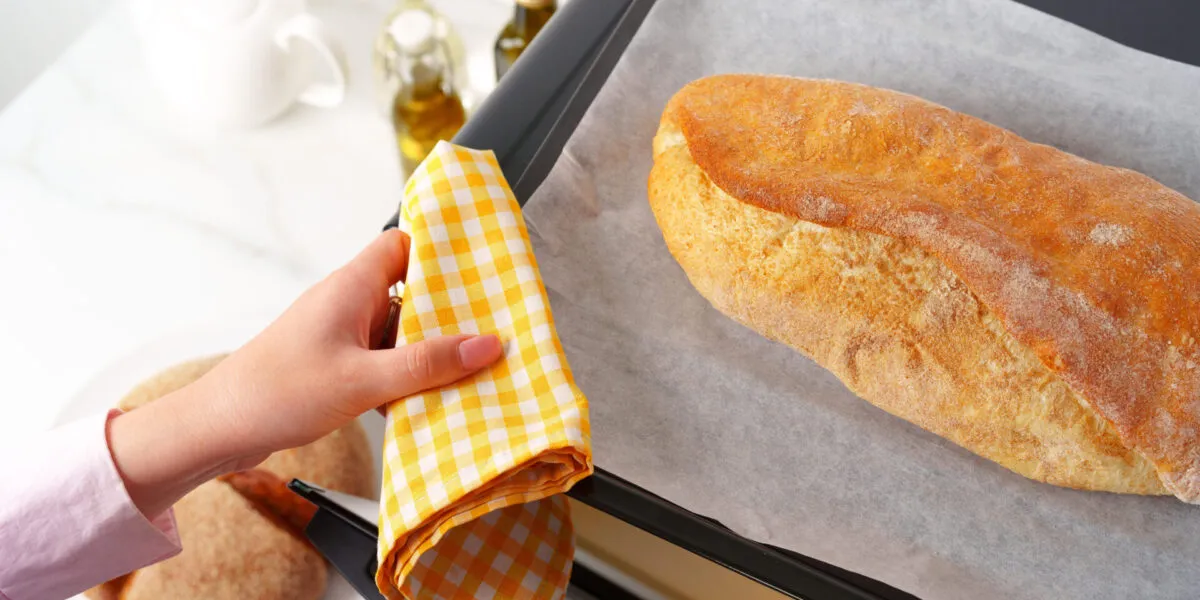 Pagnotta di pane appena sfornata su una teglia con carta forno, pronta per essere rigenerata in forno dopo lo scongelamento.