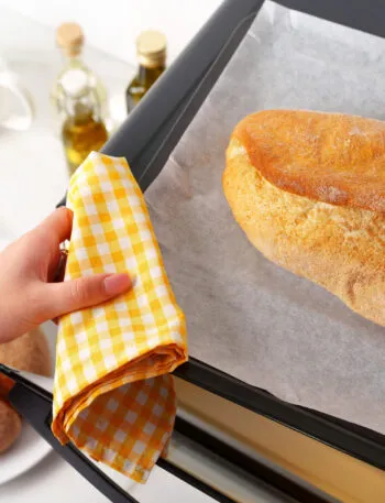 Pagnotta di pane appena sfornata su una teglia con carta forno, pronta per essere rigenerata in forno dopo lo scongelamento.