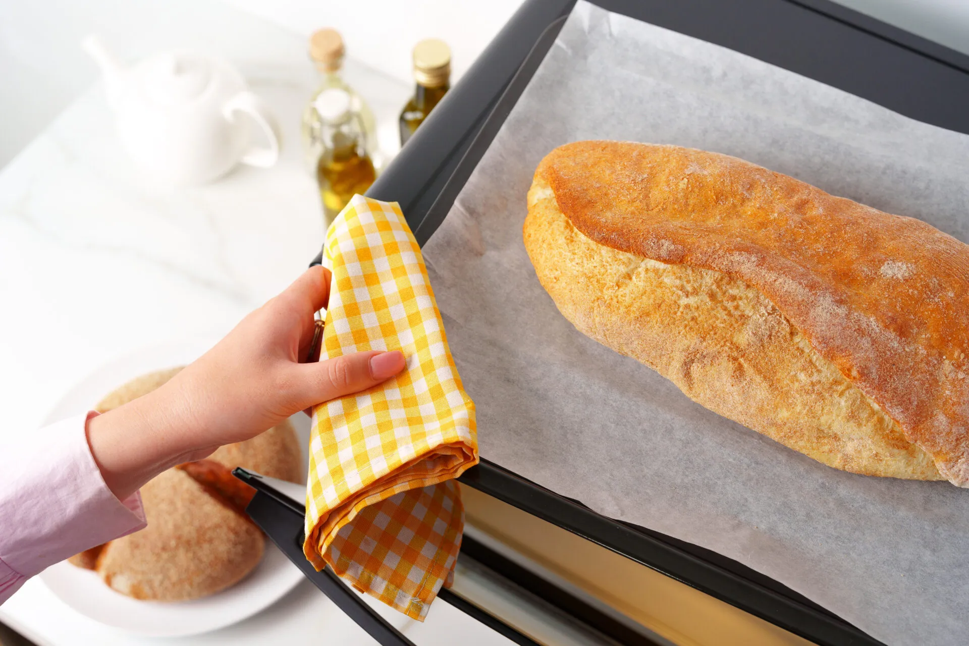 Pagnotta di pane appena sfornata su una teglia con carta forno, pronta per essere rigenerata in forno dopo lo scongelamento.