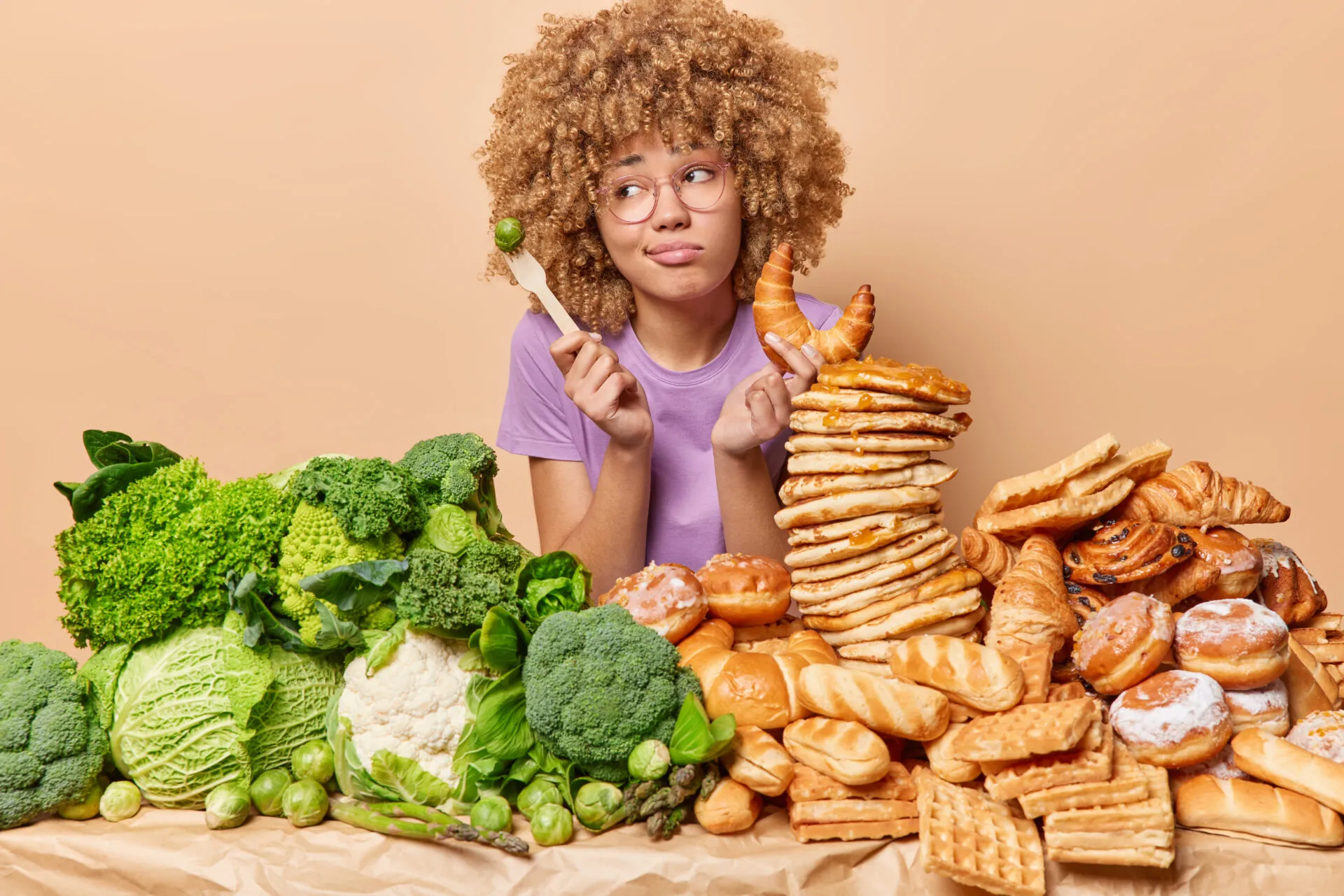 Donna indecisa tra verdure e alimenti ricchi di carboidrati come pane, croissant e pancake, simbolo della scelta di eliminare i carboidrati dalla dieta.