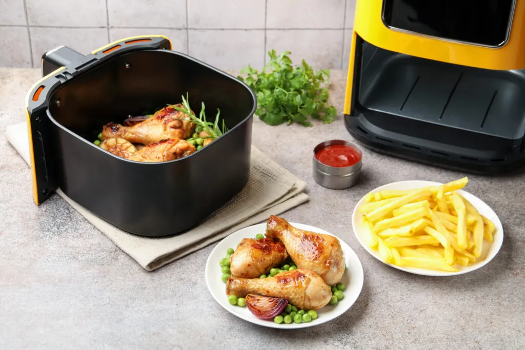 Friggitrice ad aria con pollo arrosto e patatine croccanti, metodo di cottura moderno a basso utilizzo di olio.