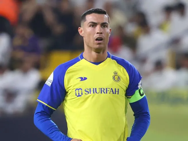 Cristiano Ronaldo in campo con la maglia dell'Al Nassr durante una partita, mentre osserva l'azione di gioco.