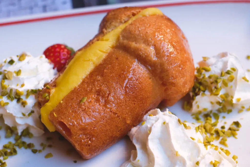 Babà napoletano con crema e panna, simbolo della pasticceria campana e dei dolci tradizionali del Sud Italia.