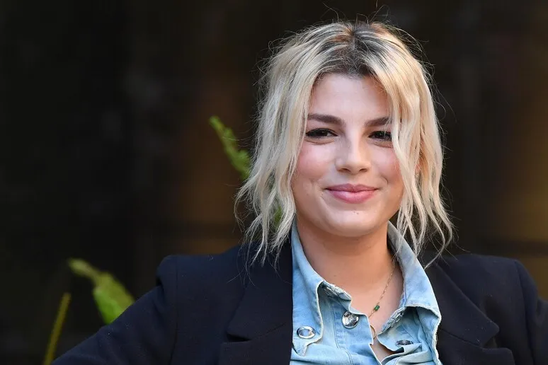 Emma Marrone posa per un ritratto con capelli biondi raccolti in modo informale, camicia in denim e blazer scuro.