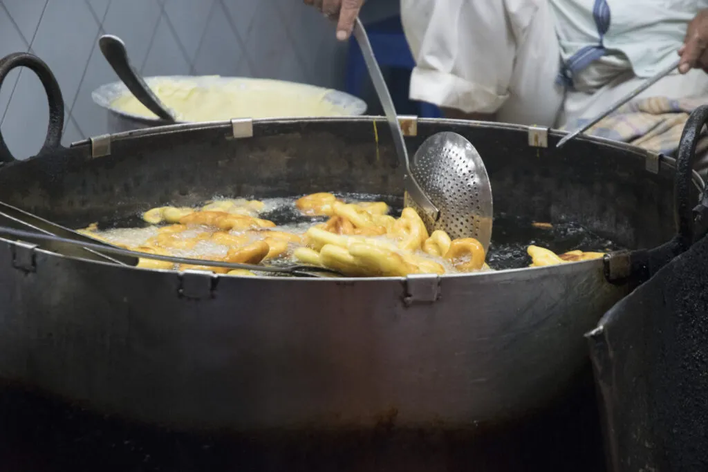 Cottura per frittura in olio bollente con alimenti dorati e croccanti, metodo tradizionale amato in tutto il mondo.