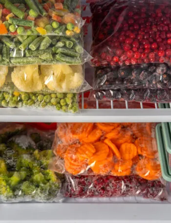 Sacchetti con verdure e frutta congelate ordinatamente sistemati nel freezer per una corretta conservazione degli alimenti.