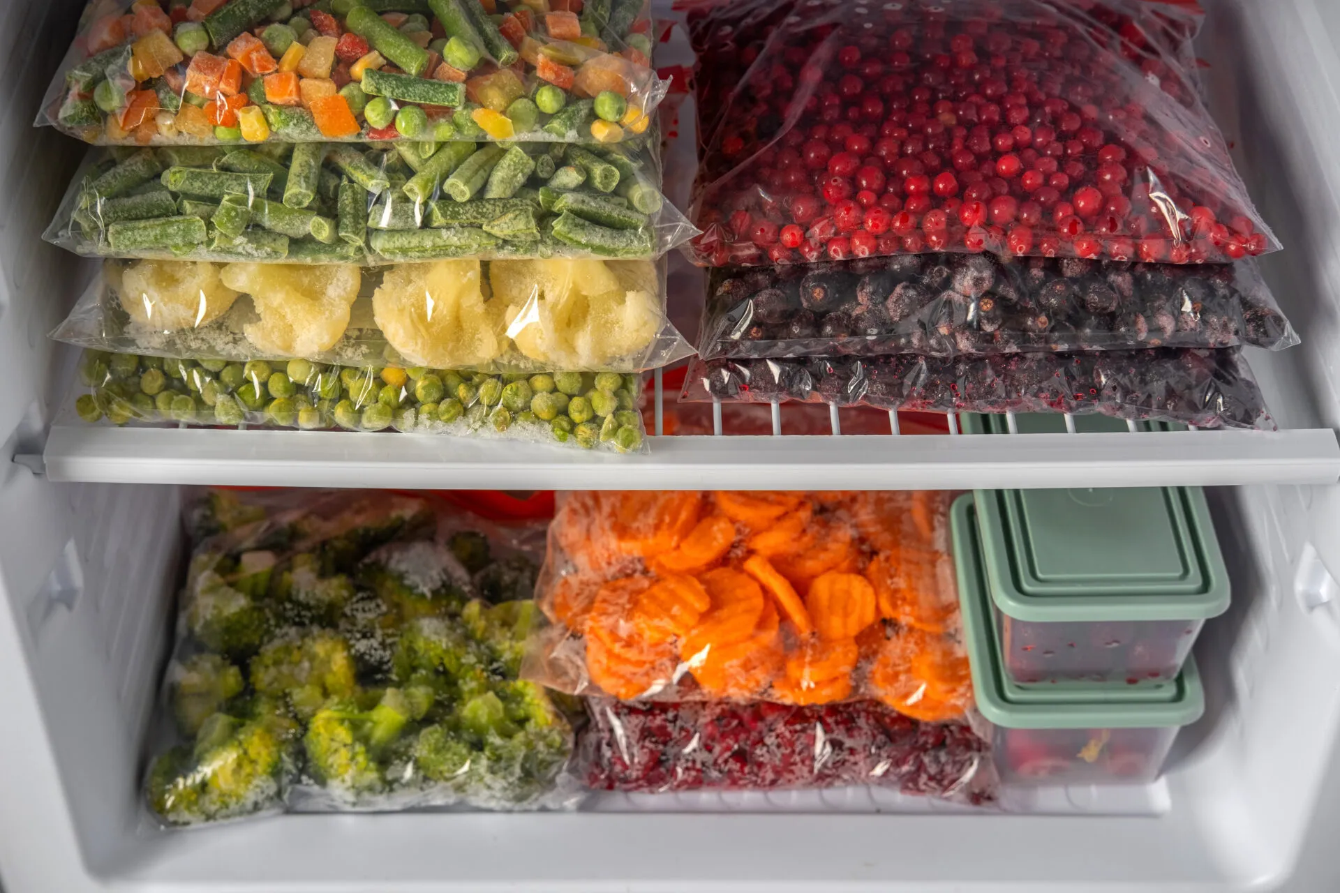 Sacchetti con verdure e frutta congelate ordinatamente sistemati nel freezer per una corretta conservazione degli alimenti.