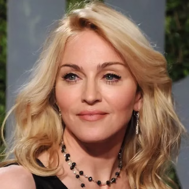 Madonna posa per un ritratto fotografico con capelli biondi e abbigliamento elegante, guardando verso l'obiettivo.