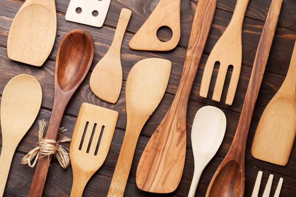 Utensili da cucina in legno naturale, inclusi mestoli, spatole e cucchiai, ideali per pentole e padelle antiaderenti.