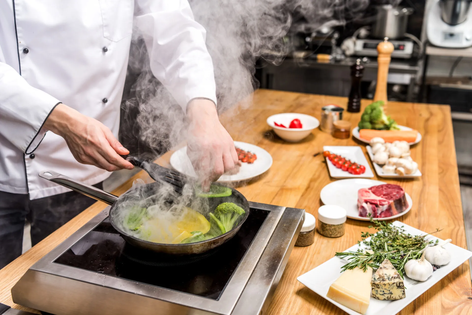 Chef mentre cucina verdure in padella, esempio di metodo di cottura tradizionale utilizzato nella cucina moderna.