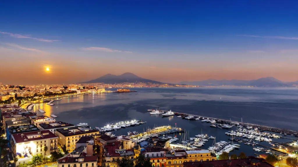 Panorama di Napoli al tramonto con il Vesuvio sullo sfondo, città dove cresce la popolarità dei ristoranti fit e delle poke bowl.