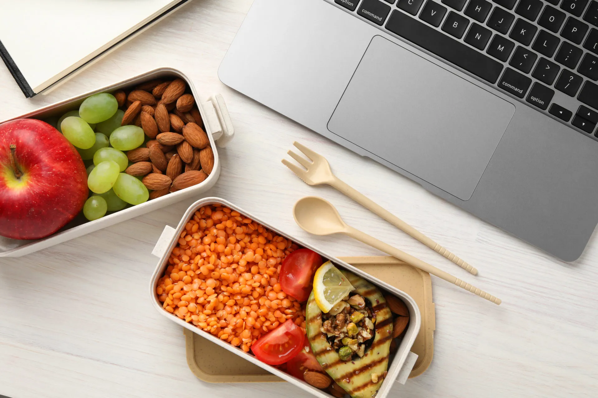 Lunch box per il pranzo in ufficio con lenticchie rosse, melanzana grigliata, pomodorini, mandorle, mela e uva, ideale per un pasto fit e sano.