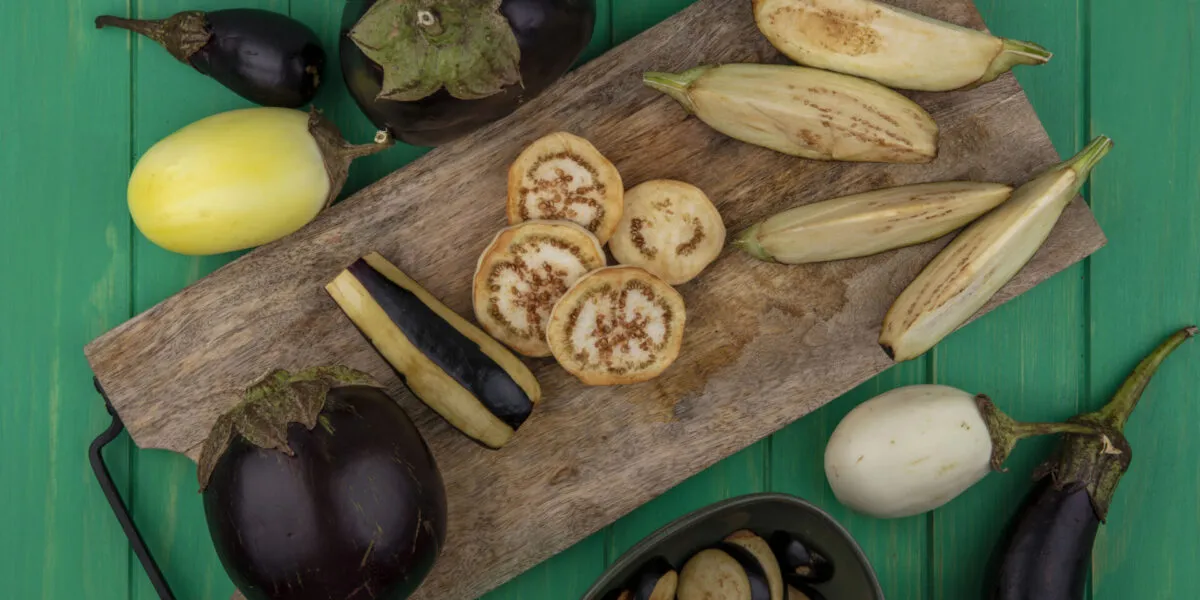 Melanzane fresche viola e bianche tagliate su tagliere in legno, ingrediente protagonista di ricette leggere con melanzane e piatti fit estivi.