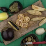 Melanzane fresche viola e bianche tagliate su tagliere in legno, ingrediente protagonista di ricette leggere con melanzane e piatti fit estivi.