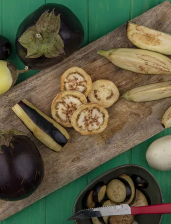 Melanzane fresche viola e bianche tagliate su tagliere in legno, ingrediente protagonista di ricette leggere con melanzane e piatti fit estivi.