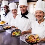 Chef e personale di cucina presentano piatti sani e colorati in un ristorante fit, con bowl ricche di verdure fresche e ingredienti equilibrati per un’alimentazione leggera e gustosa.