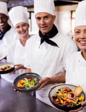 Chef e personale di cucina presentano piatti sani e colorati in un ristorante fit, con bowl ricche di verdure fresche e ingredienti equilibrati per un’alimentazione leggera e gustosa.