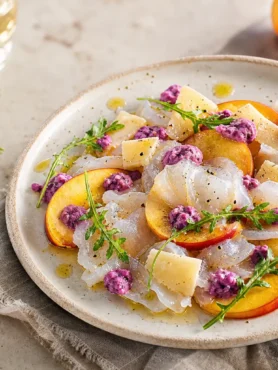 Carpaccio di baccalà con pesche noci, Parmigiano, rucola e salsa ai mirtilli