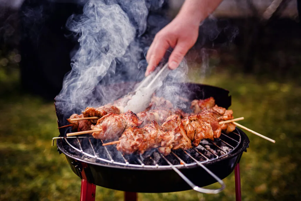Spiedini di carne su barbecue a carbone durante la cottura alla griglia, metodo tradizionale che esalta sapore e aromi.